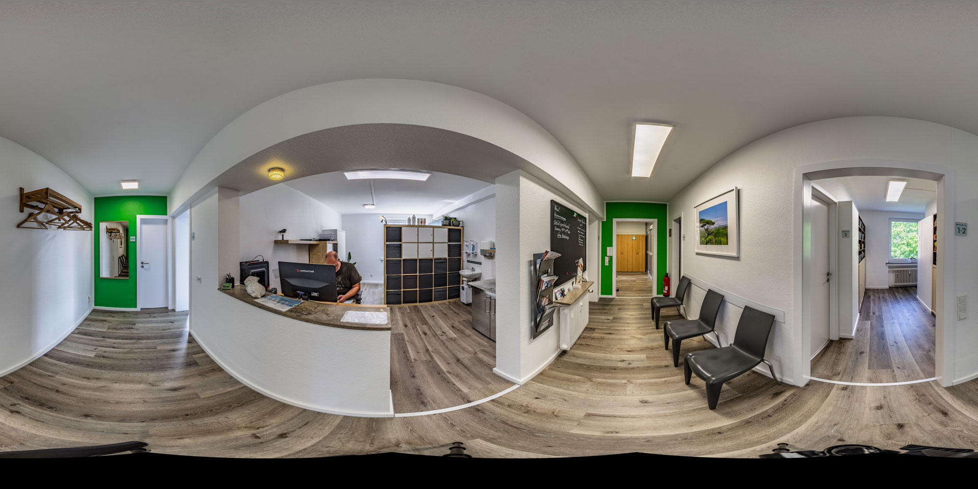 360-Grad-Büroeingang mit Holzfußboden, weißen Wänden, schwarzen Stühlen und grünen Akzenten.
