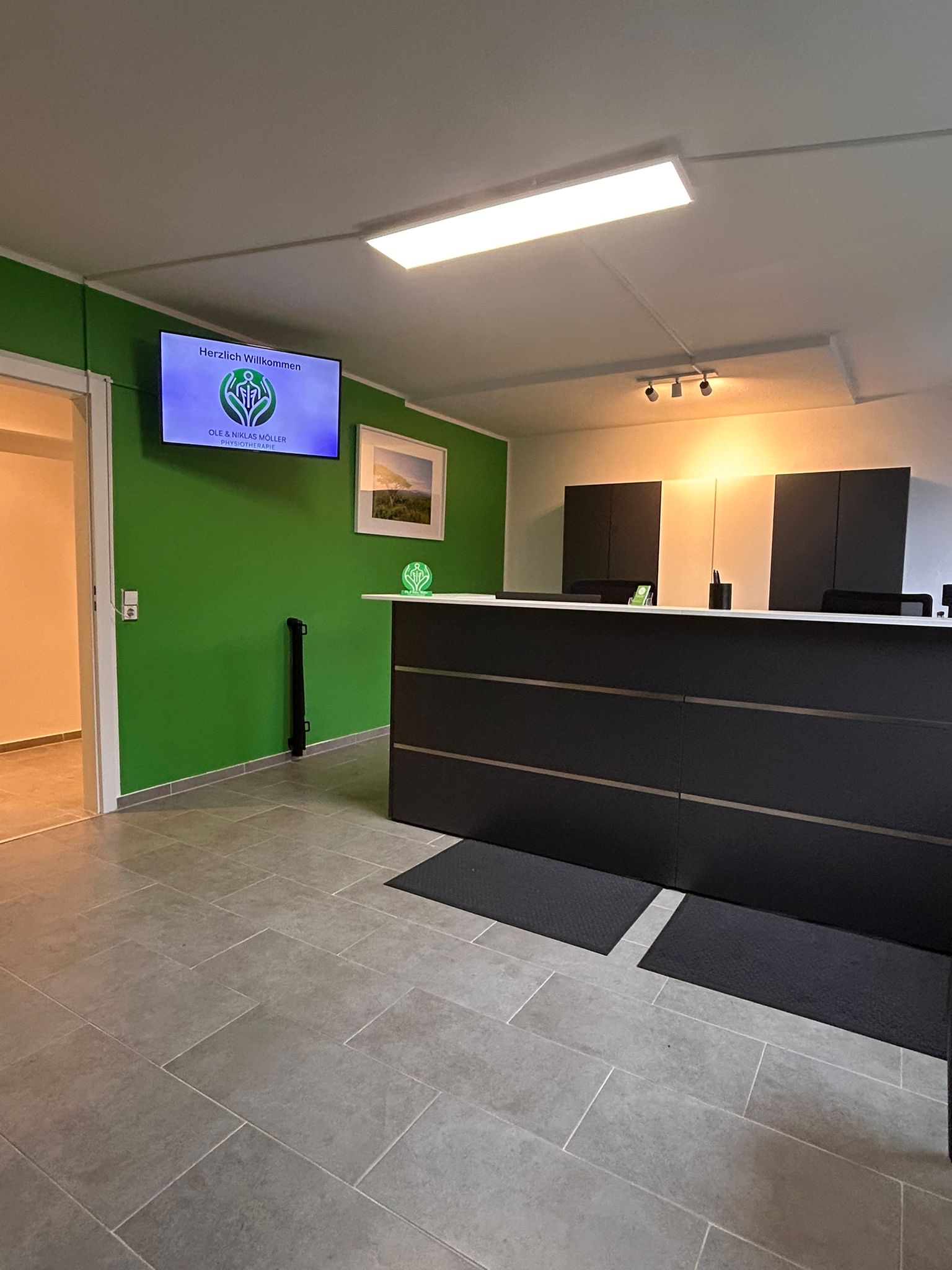 Ein leerer Empfangsbereich mit grün gestrichener Wand und moderner Theke in dunklem Grau