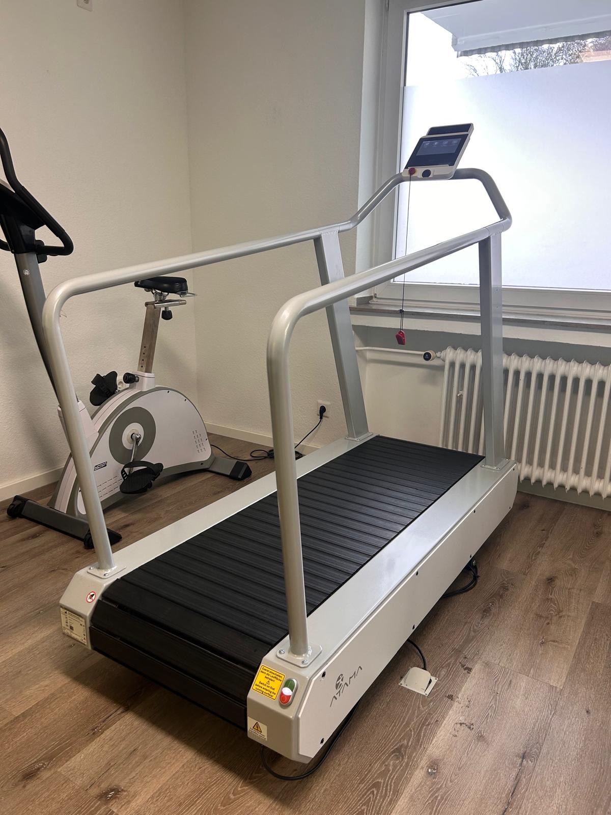 Ein leerer heller Raum mit Laufband und Heimtrainer auf einem Holzfußboden